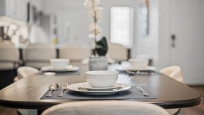A dining table with a white bowl, silverware, and a vase with white flowers. - PFR Suites - Butler|2-Story Lawrenceville Penthouse w/ Rooftop Terrace|2 King Beds /2.5 Bath|Parking (Pittsburgh)