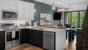 Una cocina moderna con una isla grande, electrodomésticos de acero inoxidable y vistas al exterior.