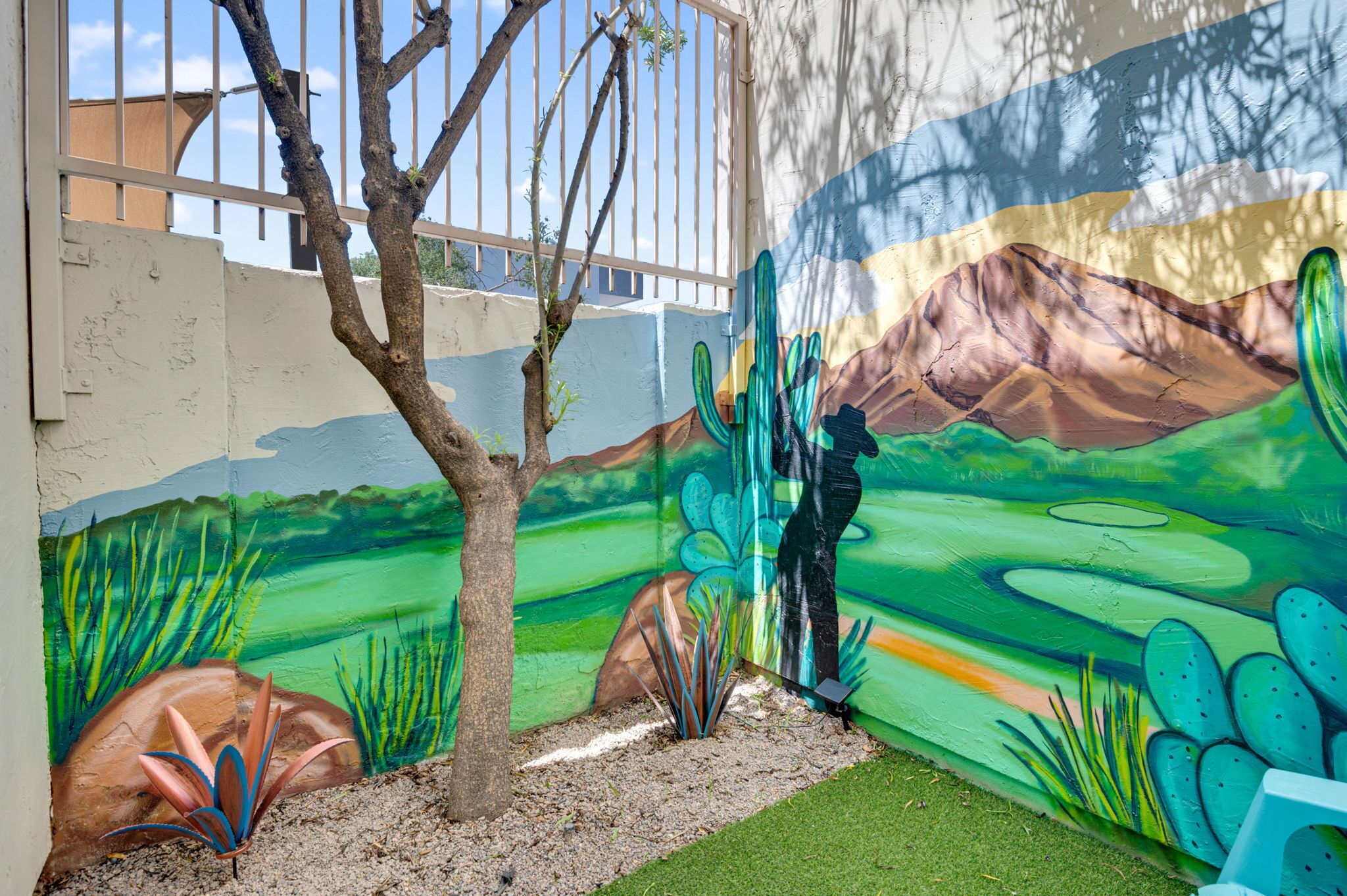 A mural of a desert landscape with a cactus and a person.
