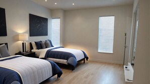 Ein modernes Schlafzimmer mit zwei Betten, einem Nachttisch, einer Lampe und einem großen Fenster.