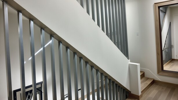 Eine moderne Treppe mit minimalistischem Design, mit Holzoptik und einem Glasgeländer.