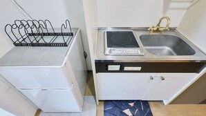A compact kitchen with a white refrigerator, a black wire rack, a stainless steel sink with a gold faucet, and a built-in induction cooktop. - 4min to Shinjuku, Close from Shibuya 1 ~ 2guests Tokyo CyberPunk Room (新宿区余丁町)