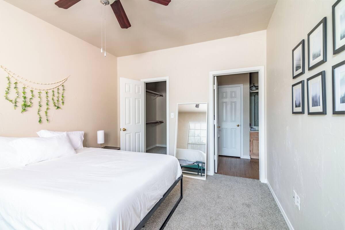 A bedroom with a bed, a ceiling fan, a wardrobe, and a bathroom visible through an open door.