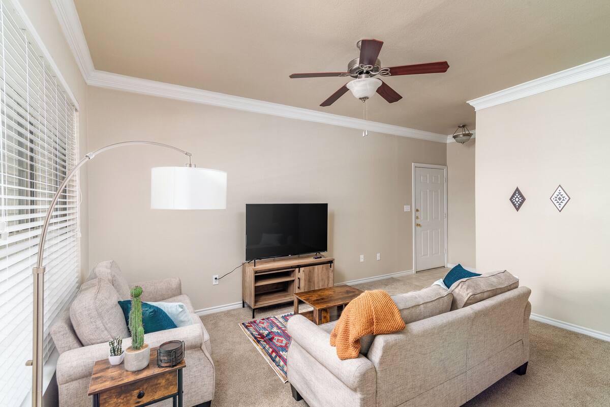 A living room with a ceiling fan, a flat-screen TV, a sofa, a coffee table, and a floor lamp.