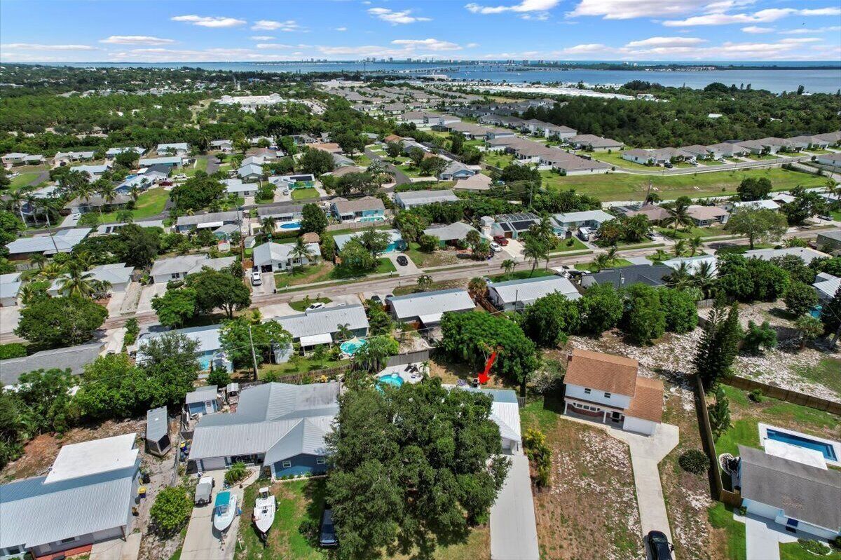 Vue aérienne d’un quartier résidentiel avec des maisons, des routes et une étendue d’eau en arrière-plan.