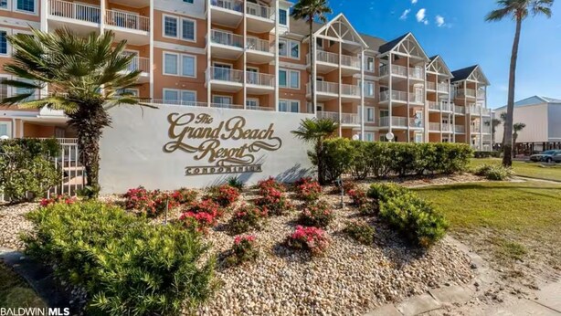 A multi-story hotel with balconies and a sign reading "The Grand Beach Resort".