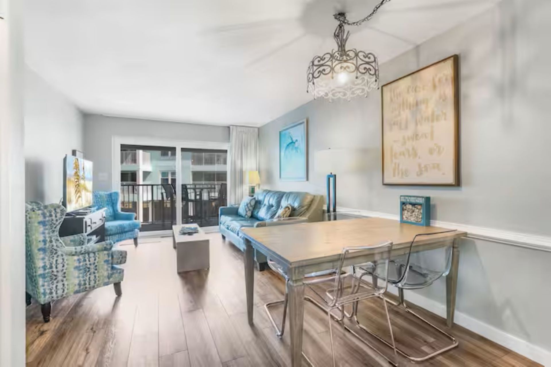 A modern living room with a dining table, blue patterned sofa, and a chandelier.