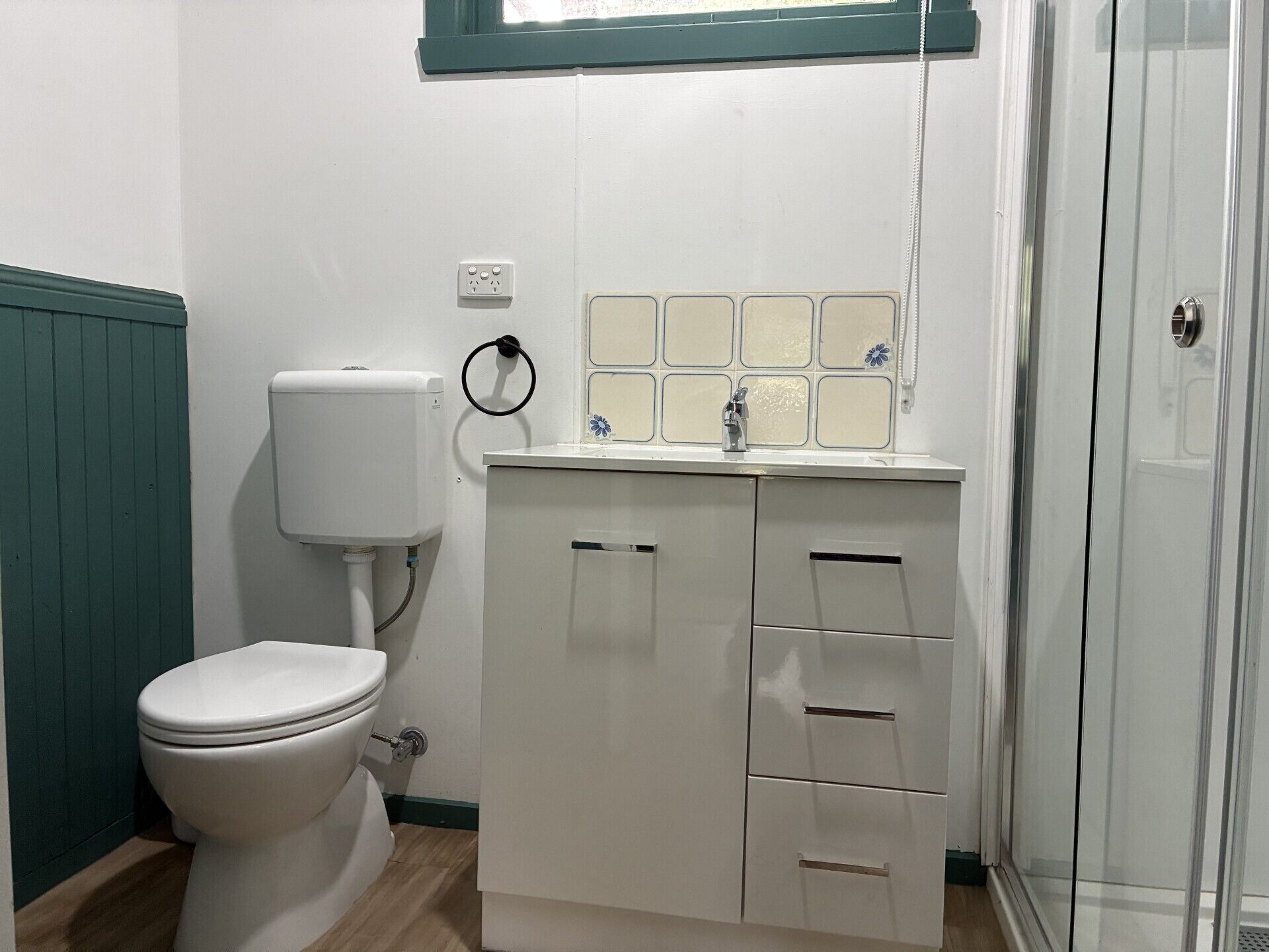 A bathroom with a toilet, a sink with a mirror, and a shower area.