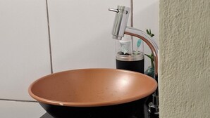 A bathroom with a black countertop, a brown ceramic sink, and a faucet. - Vilars154- Knights and Lagoon (Macaé)