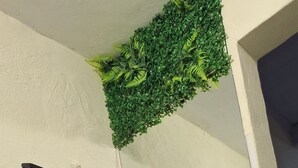 A bathroom with a black sink, white tiles, a green artificial plant, and a mirror. - Vilars154- Knights and Lagoon (Macaé)