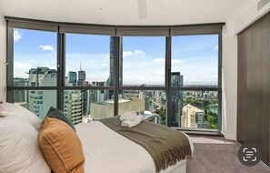Une chambre dotée d’une grande fenêtre donnant sur la ville.