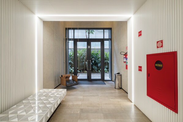 A hallway with a bench, a red fire safety cabinet, and a door leading outside.