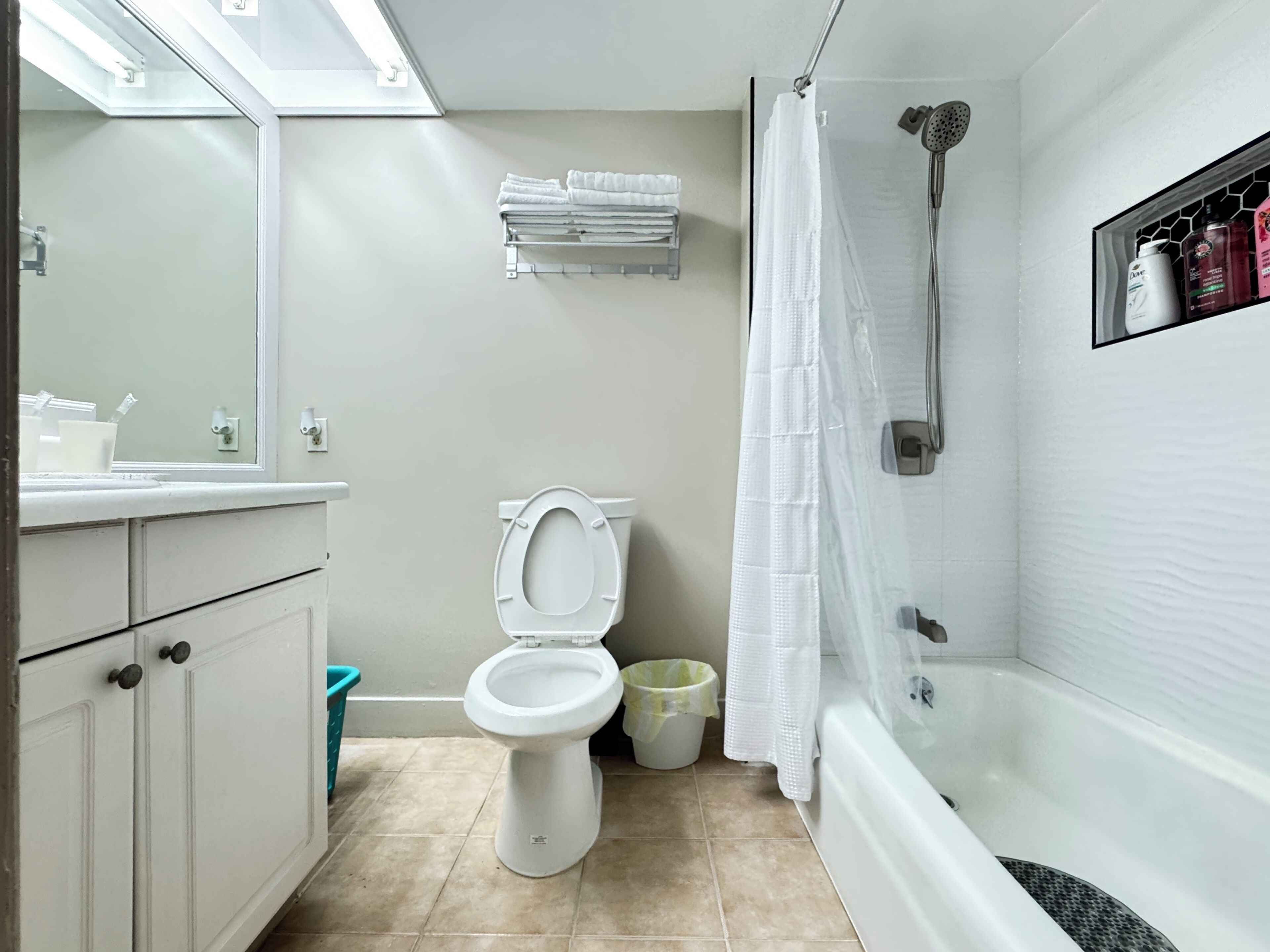Une salle de bain comprenant des toilettes, une douche, une baignoire, un lavabo, un miroir et un porte-serviettes.