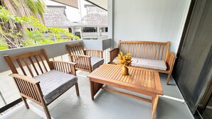 A balcony with wooden furniture and a vase of flowers. - 5 Sunshine Rental ,A quiet and comfortable studio located HIlo Heart. (Hilo)