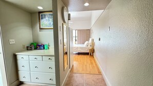 A hallway with a white dresser, a framed picture on the wall, and a bed in the background. - 5 Sunshine Rental ,A quiet and comfortable studio located HIlo Heart. (Hilo)