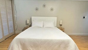 A large bed with a white headboard and two bedside tables, each with a lamp. - 5 Sunshine Rental ,A quiet and comfortable studio located HIlo Heart. (Hilo)