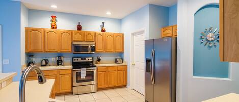 A modern kitchen with wooden cabinets, stainless steel appliances, and a blue accent wall.