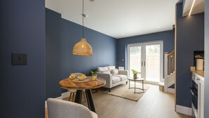 Un salon moderne comprenant un coin repas, un canapé et un escalier menant à la cuisine.