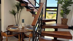 A modern interior with a wooden staircase, dining table with chairs, and potted plants.