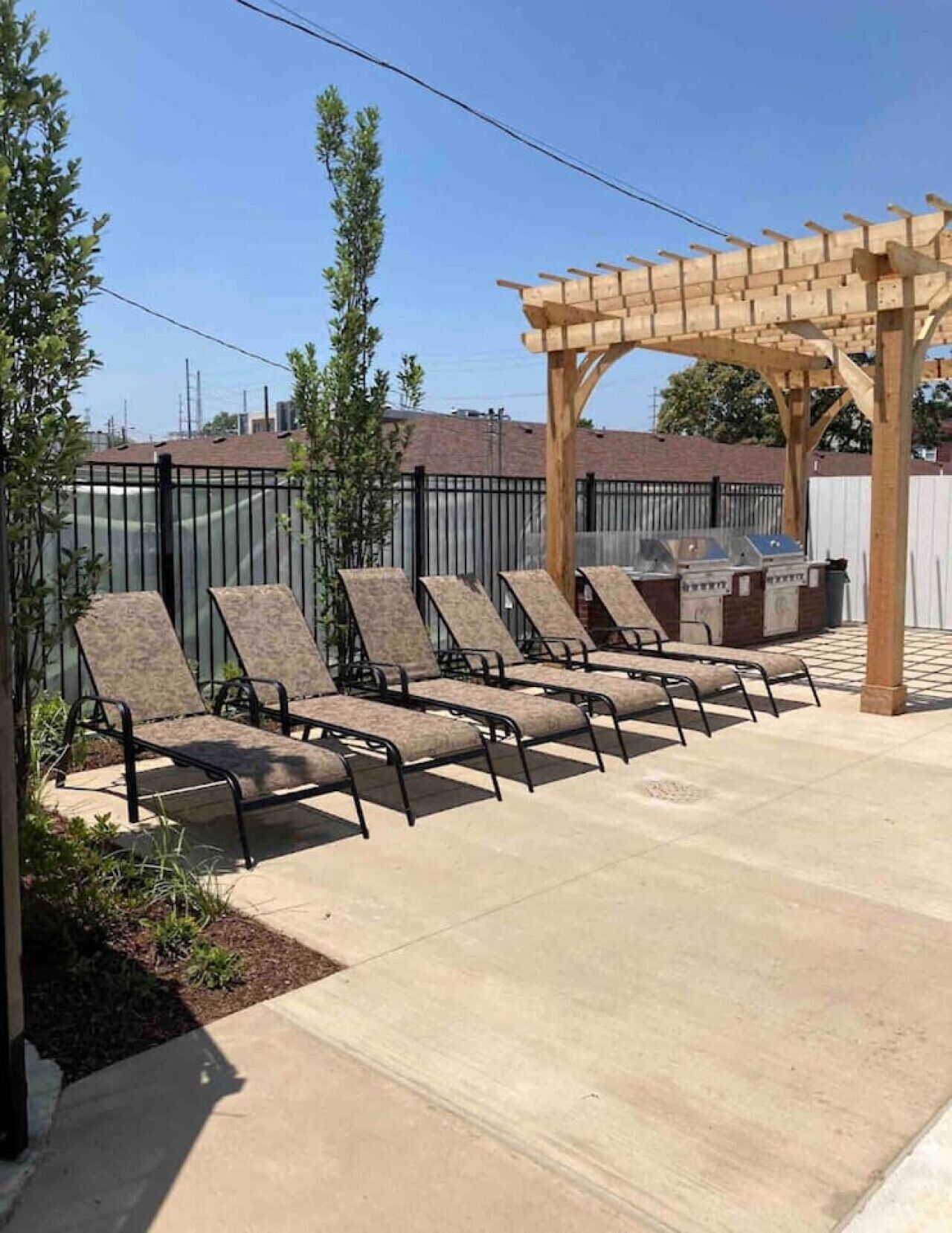 Un patio al aire libre con seis sillones, una pérgola de madera y una parrilla.