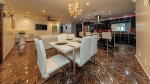 A modern dining area with a chandelier, marble flooring, and white furniture.