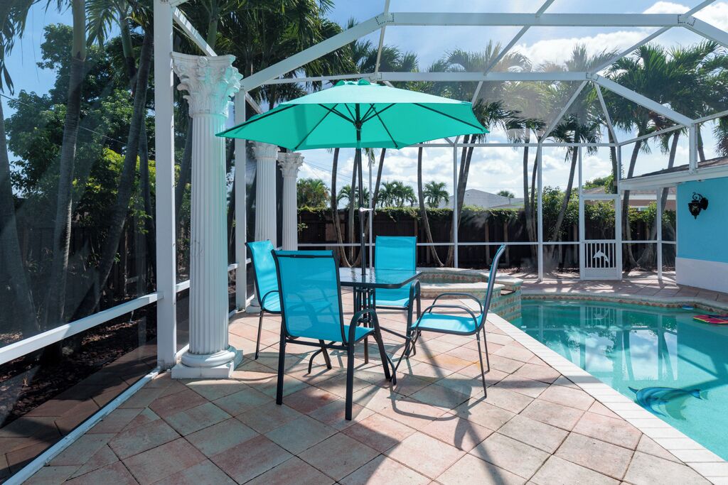 Un espace piscine extérieur doté d’un patio couvert, de chaises et d’une table.