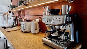 A kitchen with a coffee machine, toaster, and wooden shelves with kitchen utensils. - Hanmer Glamping (Hanmer Springs)
