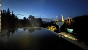 A hot tub with a clear view of the surrounding landscape, including trees and a distant mountain range. - Hanmer Glamping (Hanmer Springs)