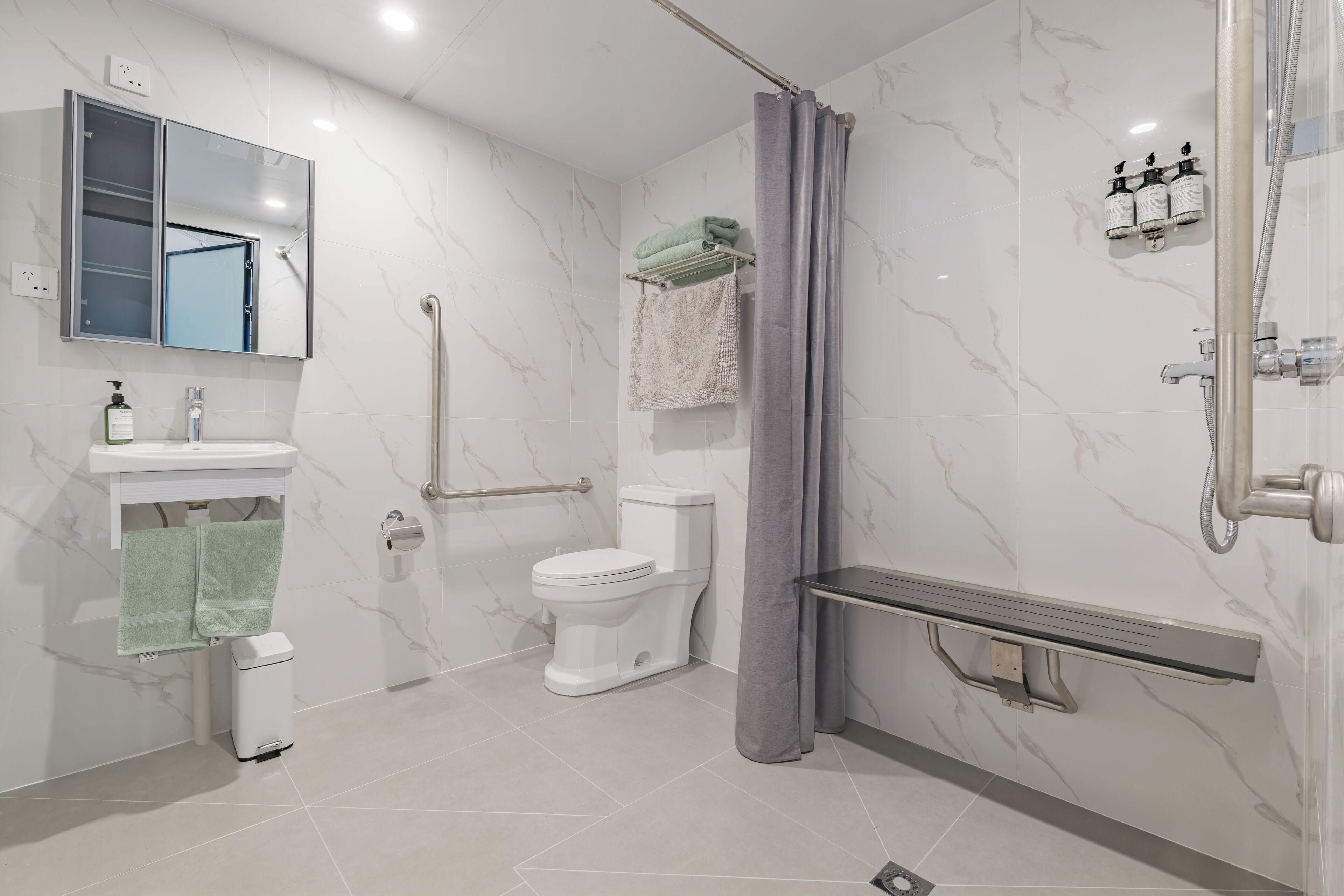 Une salle de bain moderne équipée de toilettes, d’un lavabo, d’un miroir et d’un espace douche.