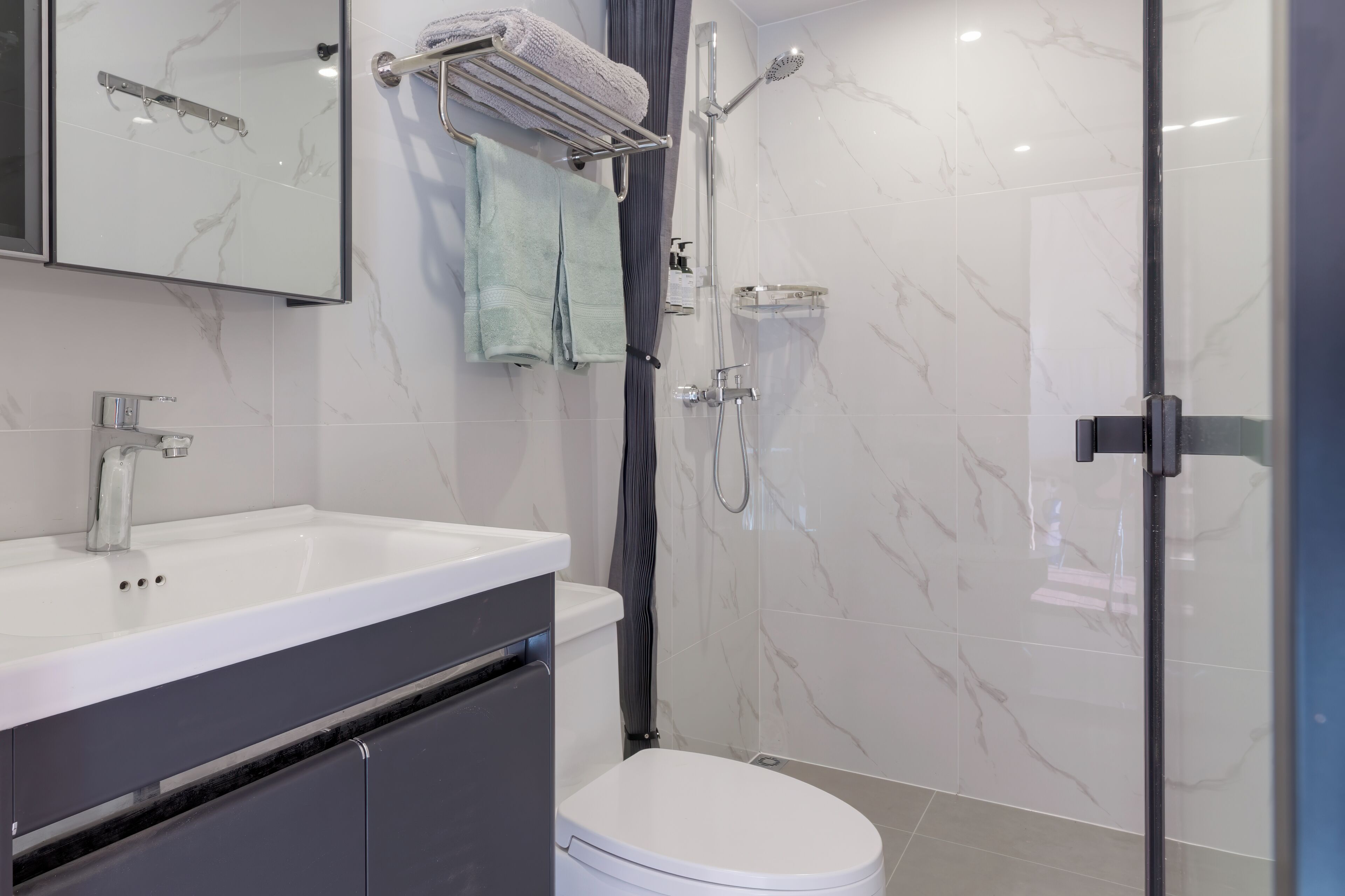 A modern bathroom with a white sink, a toilet, and a shower area.