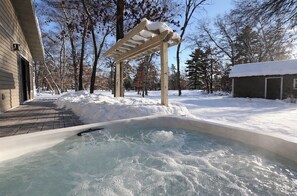 A hot tub in a snowy outdoor setting with a wooden pergola overhead. - NEW! All Season Hot Tub, Fire Pit, Golf Course, Breezy Point (Pequot Lakes)
