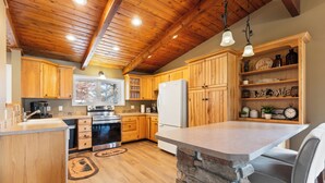 A kitchen with wooden cabinets, a stone island, and a built-in refrigerator. - NEW! All Season Hot Tub, Fire Pit, Golf Course, Breezy Point (Pequot Lakes)