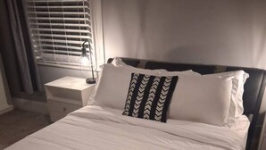 Un lit bien fait, avec des draps blancs et des serviettes enroulées posées sur le pied de lit.