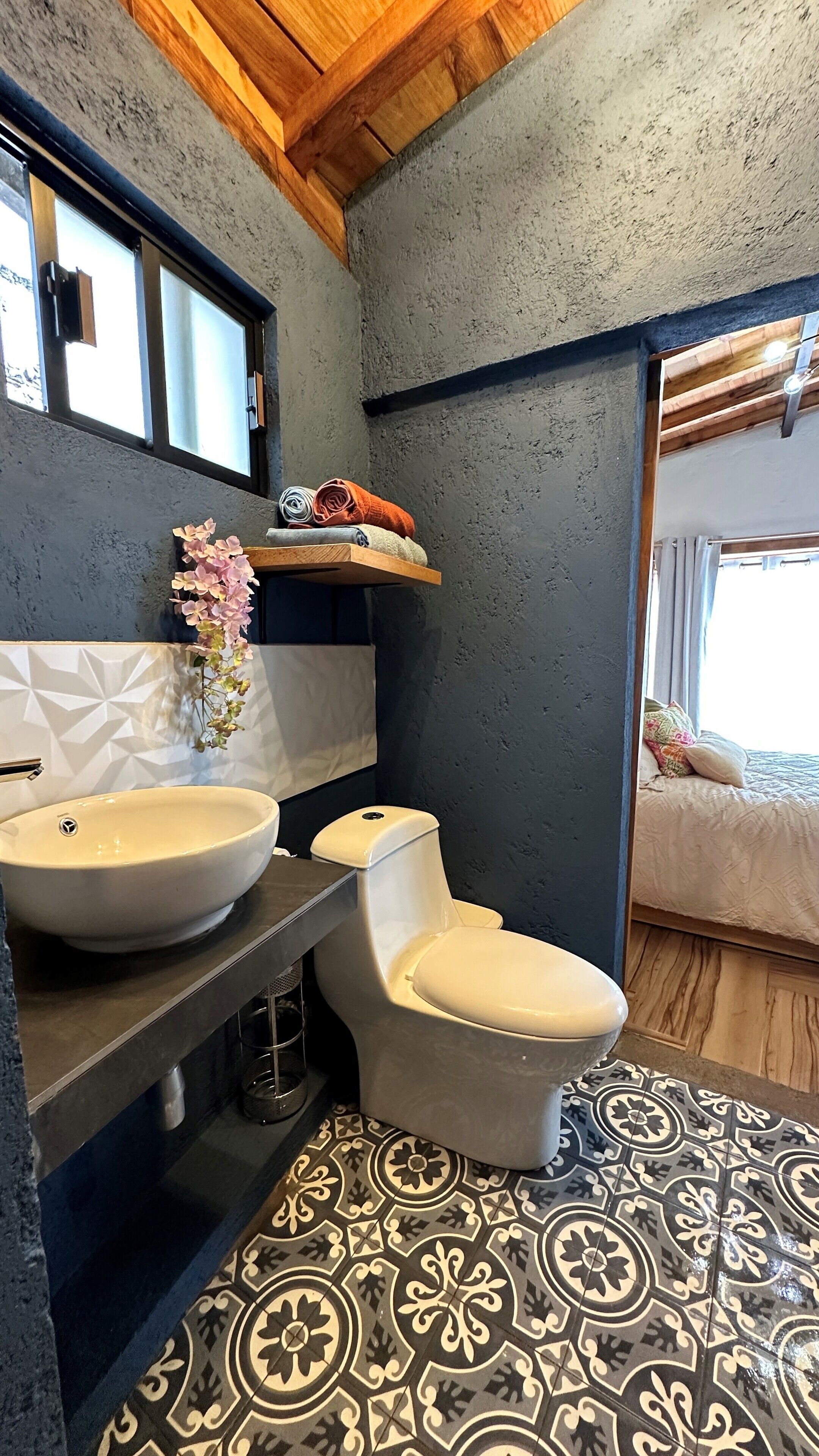 A bathroom with a modern design, featuring a large sink, toilet, and a shower area.