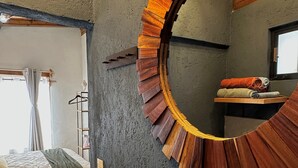 A room with a circular wooden mirror on the wall, a bed with a patterned bedspread, a wooden floor, and a window with curtains. - Cozy Loft Maria Bonita, central to the Magical Town of Valle de Bravo (Valle de Bravo)