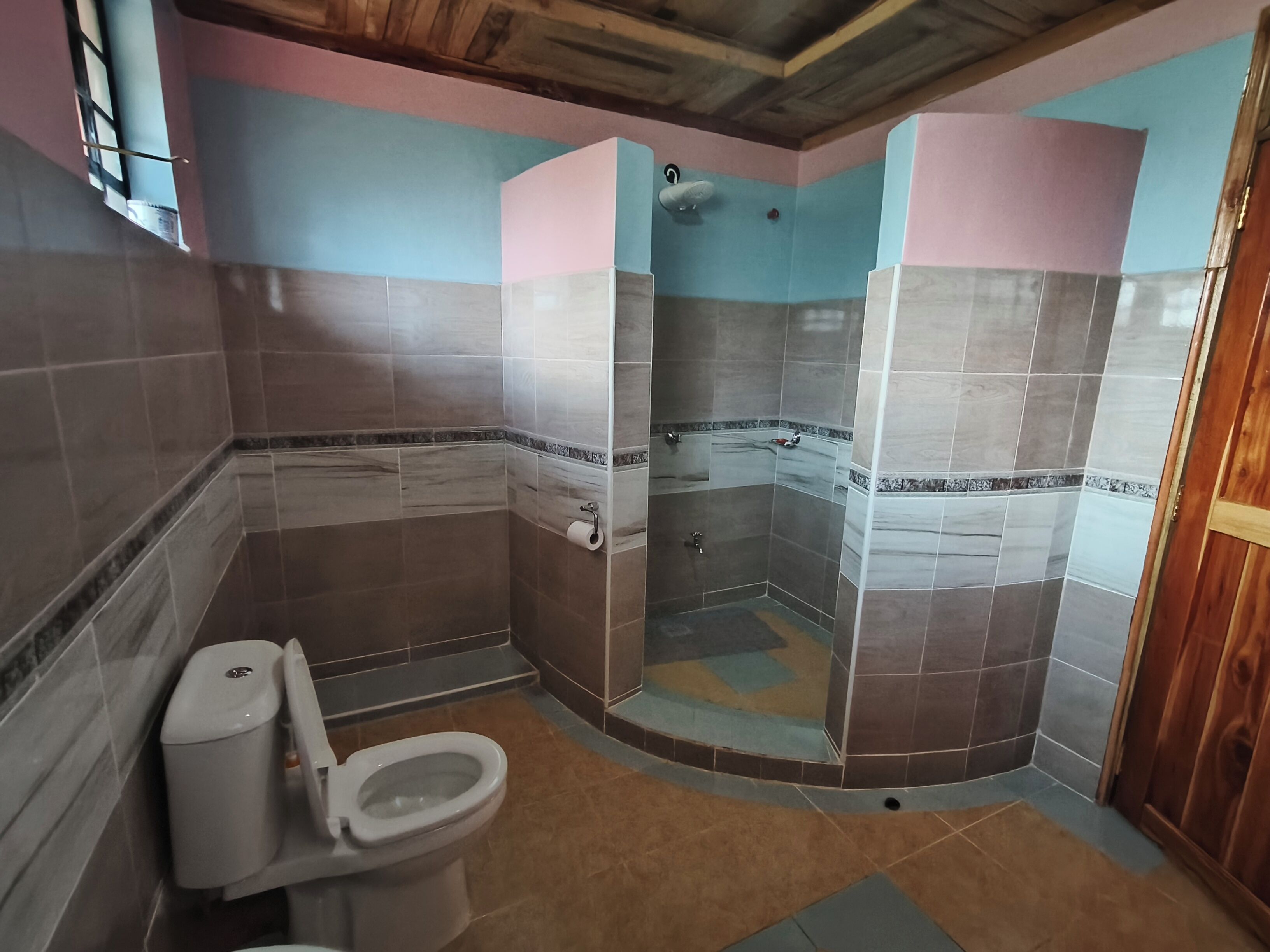 Un baño con inodoro, ducha y paredes de azulejos.