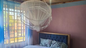Ein Schlafzimmer mit Bett, einer Pendelleuchte und Blick durch ein Fenster.