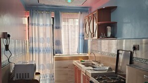 Eine kleine Küche mit einem Gaskochfeld, einem Kühlschrank und einer Spüle.