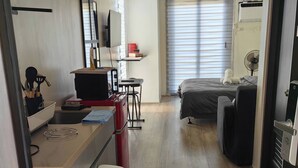 A compact hotel room with a kitchenette, a bed, a desk, and a large window. - Studio Unit with Balcony + City & Mountain Views + Fast WiFi | Near IT Park (Cebu City)