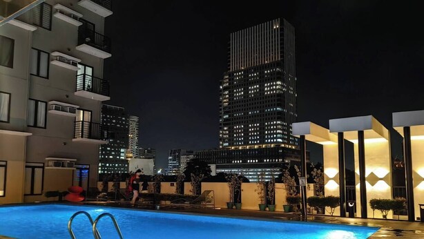 A rooftop pool with a view of a cityscape at night. - Studio Unit with Balcony + City & Mountain Views + Fast WiFi | Near IT Park (Cebu City)