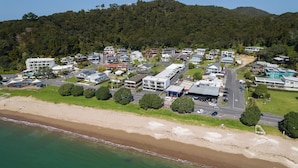 Uma área residencial costeira com casas, uma praia e uma colina arborizada ao fundo.