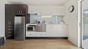 Uma cozinha moderna com eletrodomésticos de aço inoxidável, armários brancos e forno embutido.