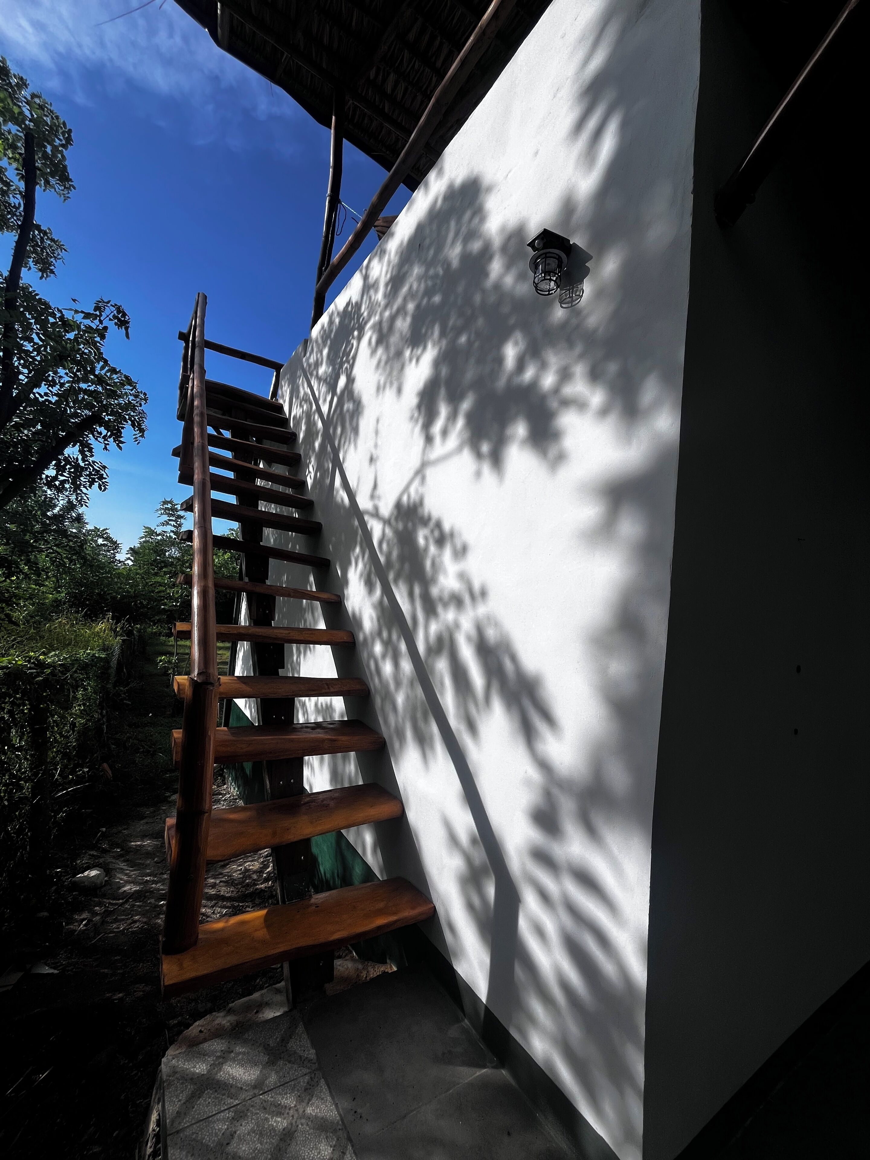 Un escalier en bois mène à un bâtiment blanc doté d’une petite fenêtre.
