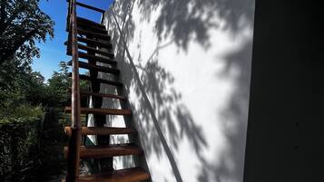 Un escalier en bois mène à un bâtiment blanc doté d’une petite fenêtre.