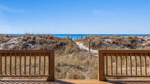 A wooden deck with a view of a beach and dunes.