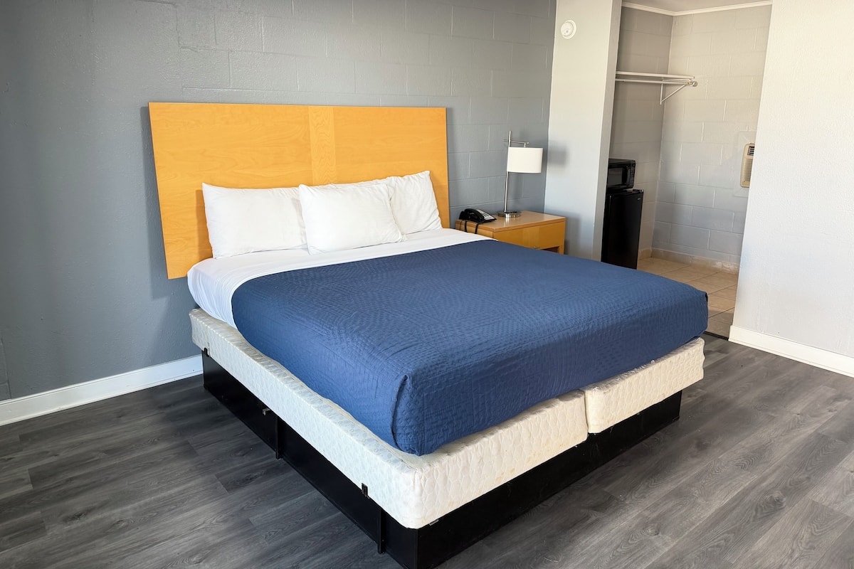 Une chambre d’hôtel moderne avec un grand lit, une tête de lit en bois, une table de chevet avec une lampe et un radiateur intégré.