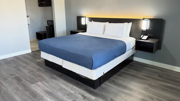A modern hotel room with a large bed, a bedside table with a phone, and a wall-mounted TV. - Budget Inn Port Lavaca (Port Lavaca)