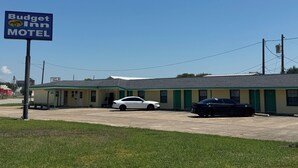 A motel with a signboard, a parking lot, and two cars parked in front. - Budget Inn Port Lavaca (Port Lavaca)