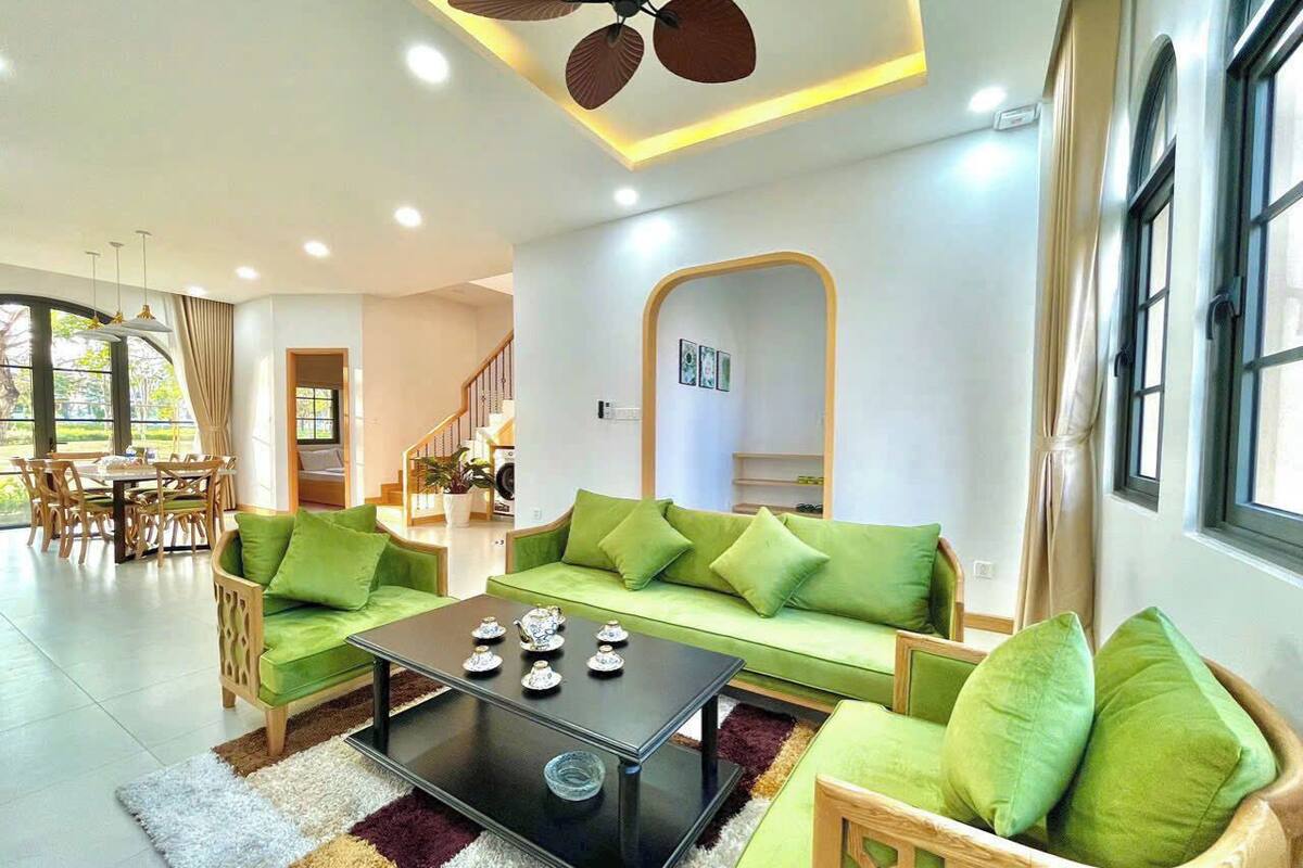 A modern living room with a green sofa set, a coffee table, and a ceiling fan.