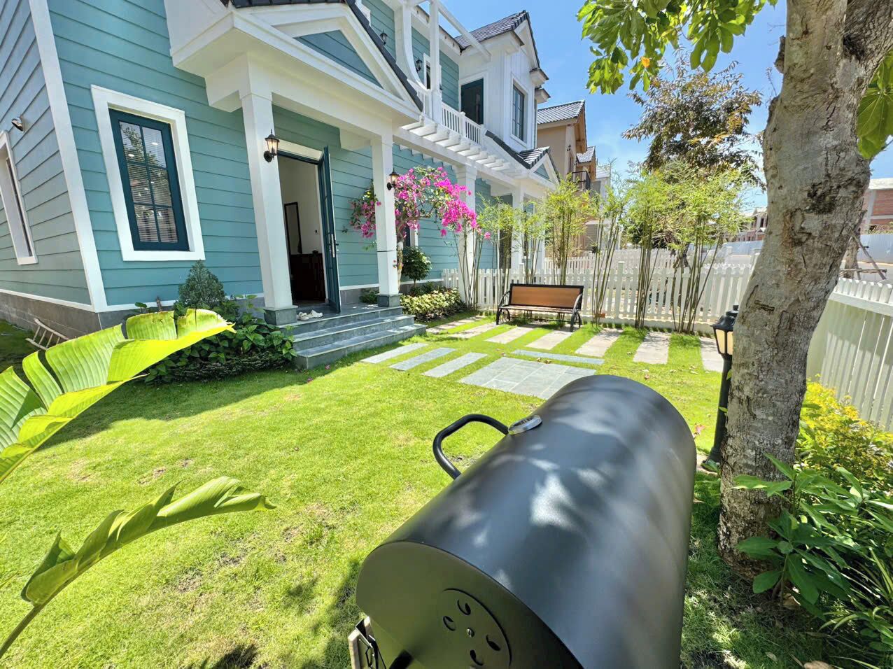 A house with a front porch, a barbecue grill, and a well-maintained lawn.